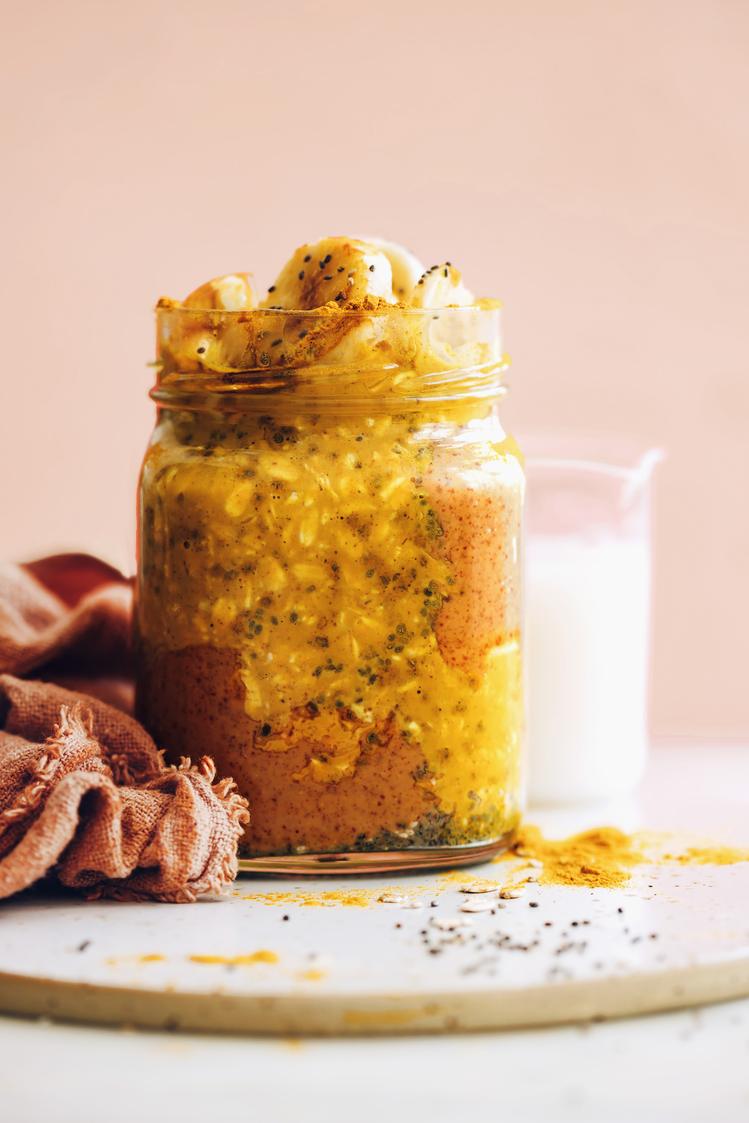 az éjszakai zab képe, tejfűszerekkel átitatva egy üvegbe, oldalán rózsaszín törülközővel