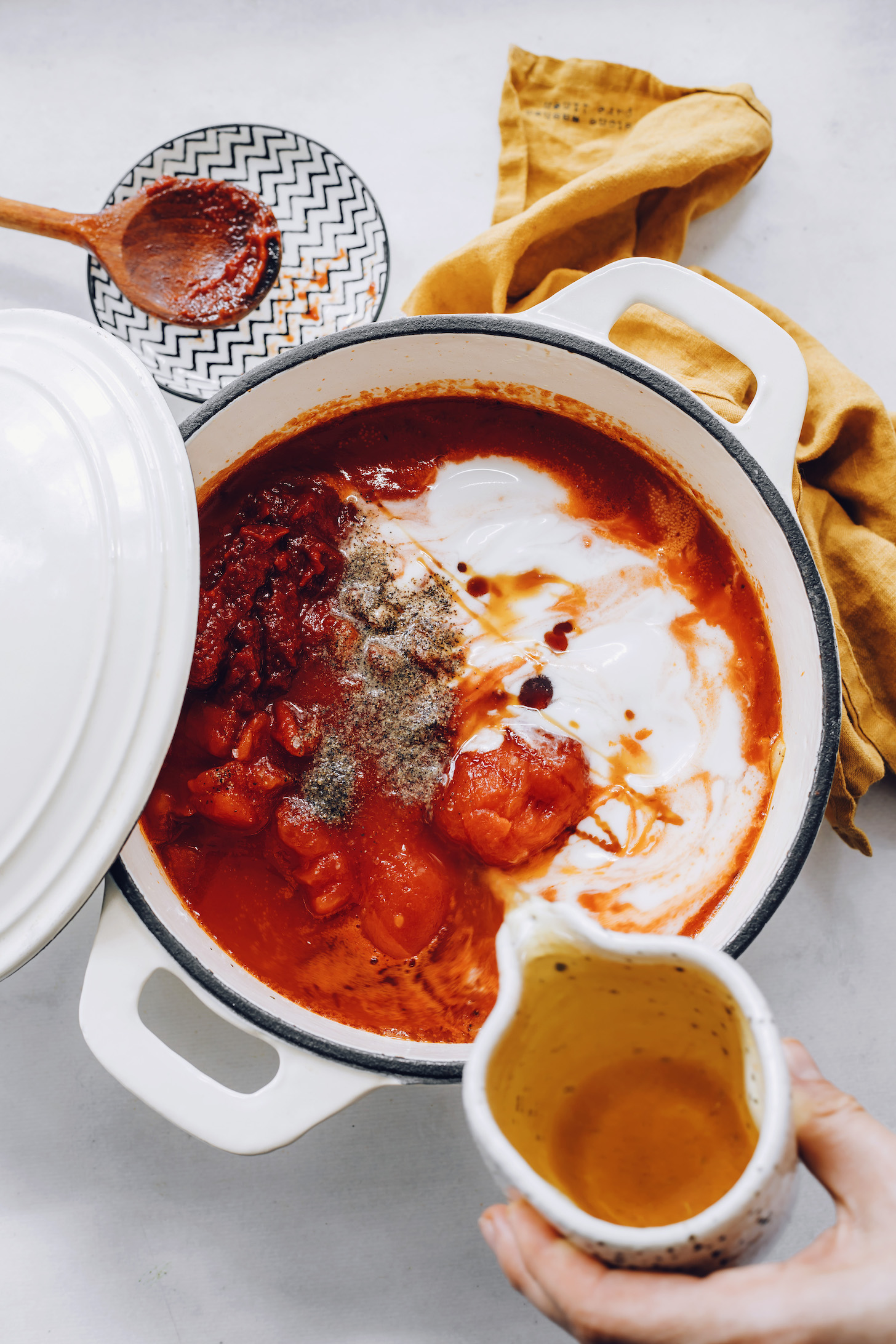 Zöldséglevest öntünk egy edénybe paradicsommal, kókusztejjel, sóval, borssal, bazsalikommal, hagymával, fokhagymával, juharsziruppal és húslevessel.