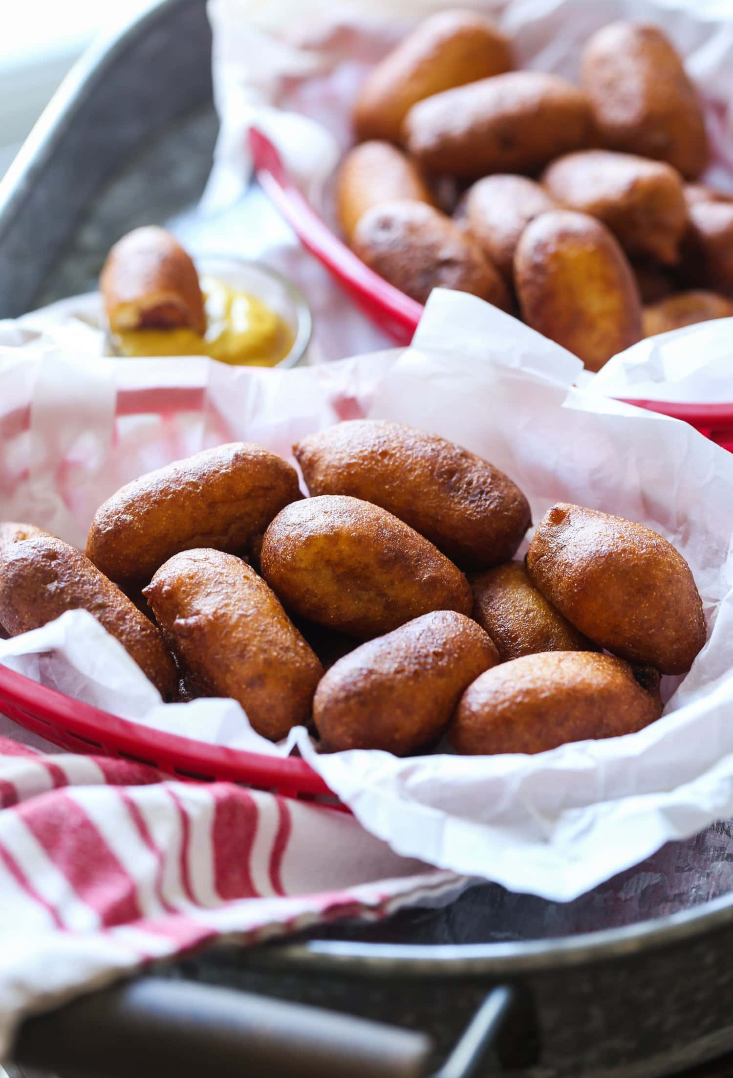 A basket of mini corn dogs with cornmeal breading.