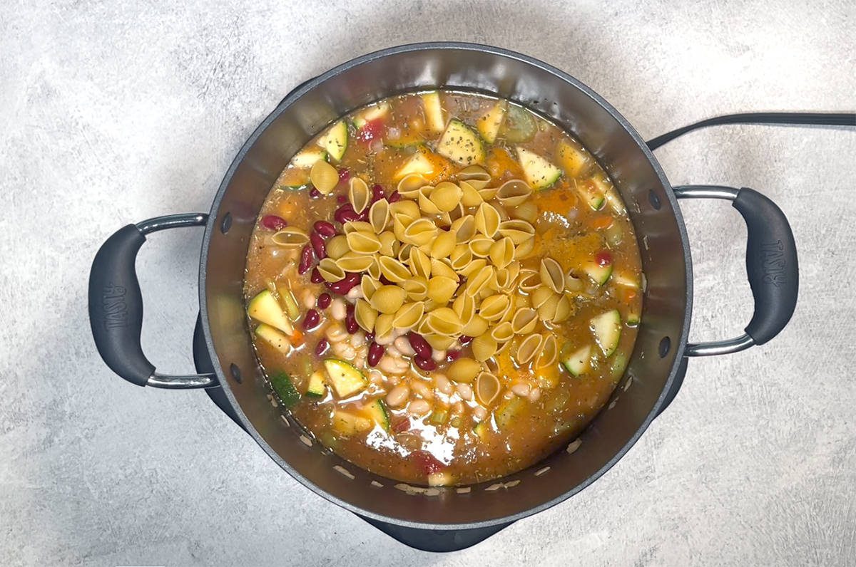 Áttekintő felvétel a minestrone levesről, amely fekete edényben készül.