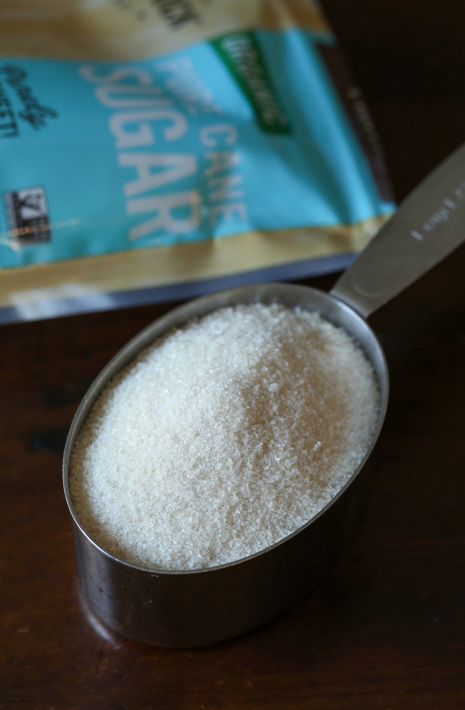 A measuring cup filled with cane sugar, which will be combined with salt for the coating.