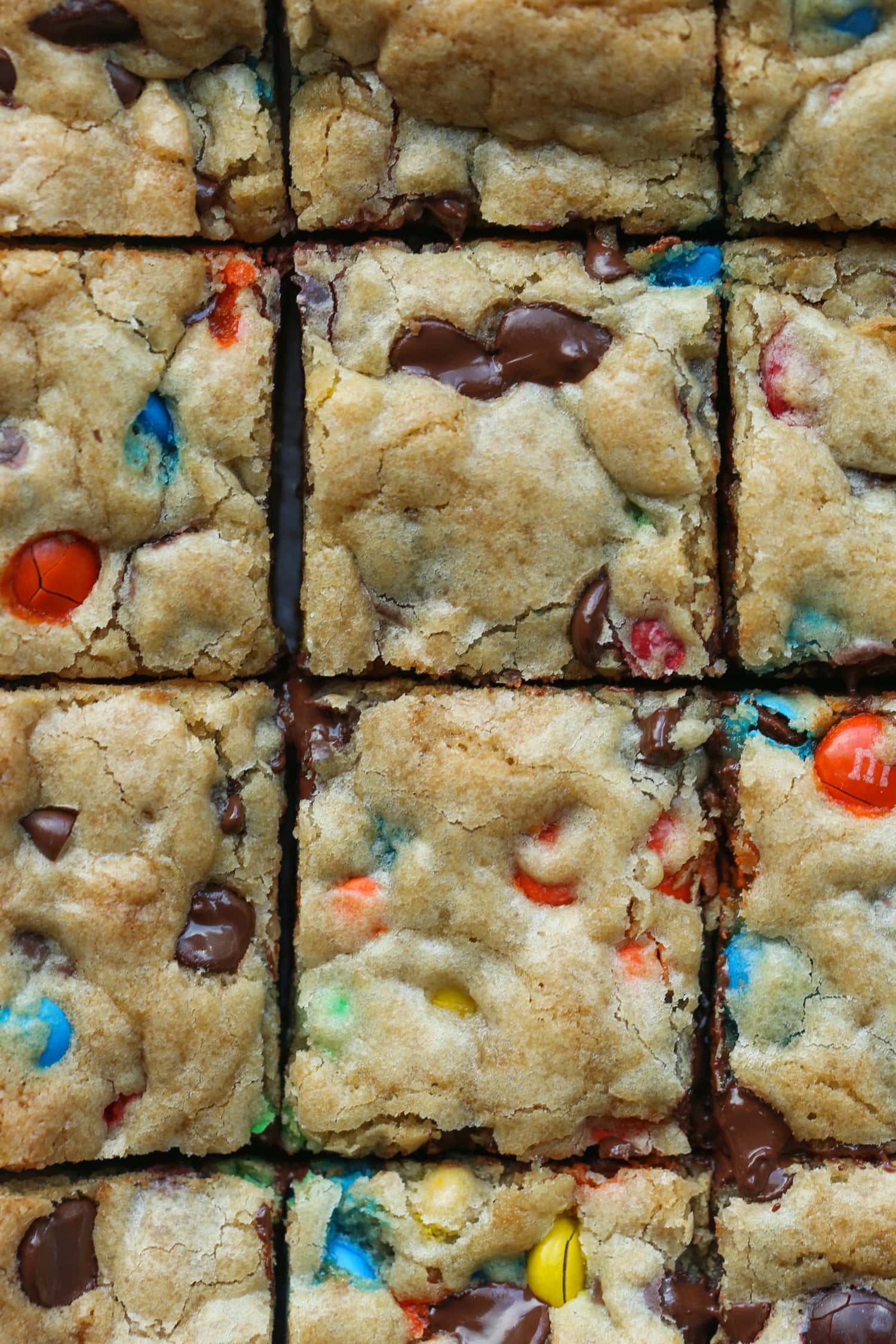 M&M Cookie Bars cut into squares on a cutting board from overhead 
